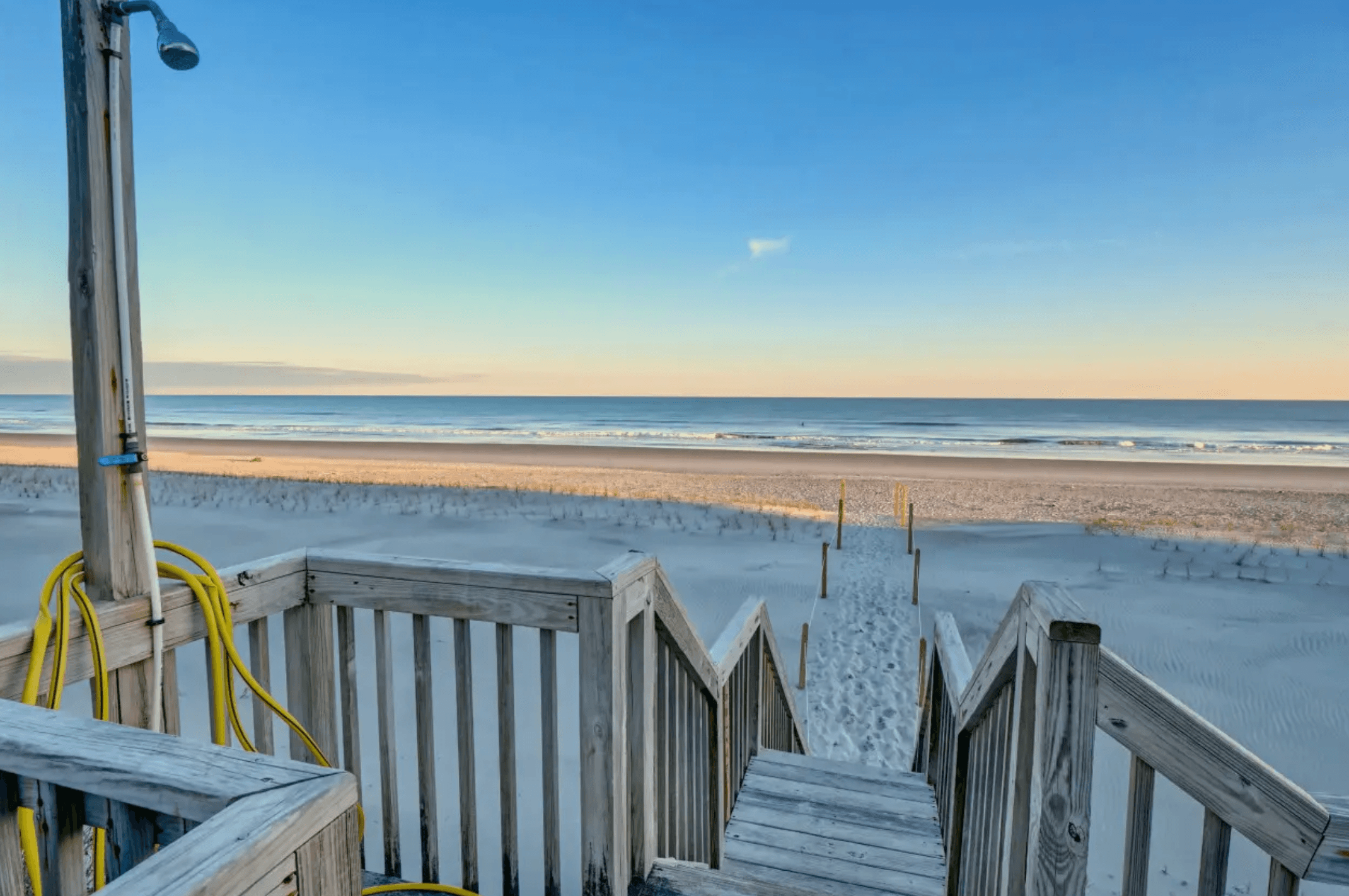 Wooden stairs from a Queens Grant beach access down to the empty Atlantic beach at sunrise, outdoor shower on the walkway