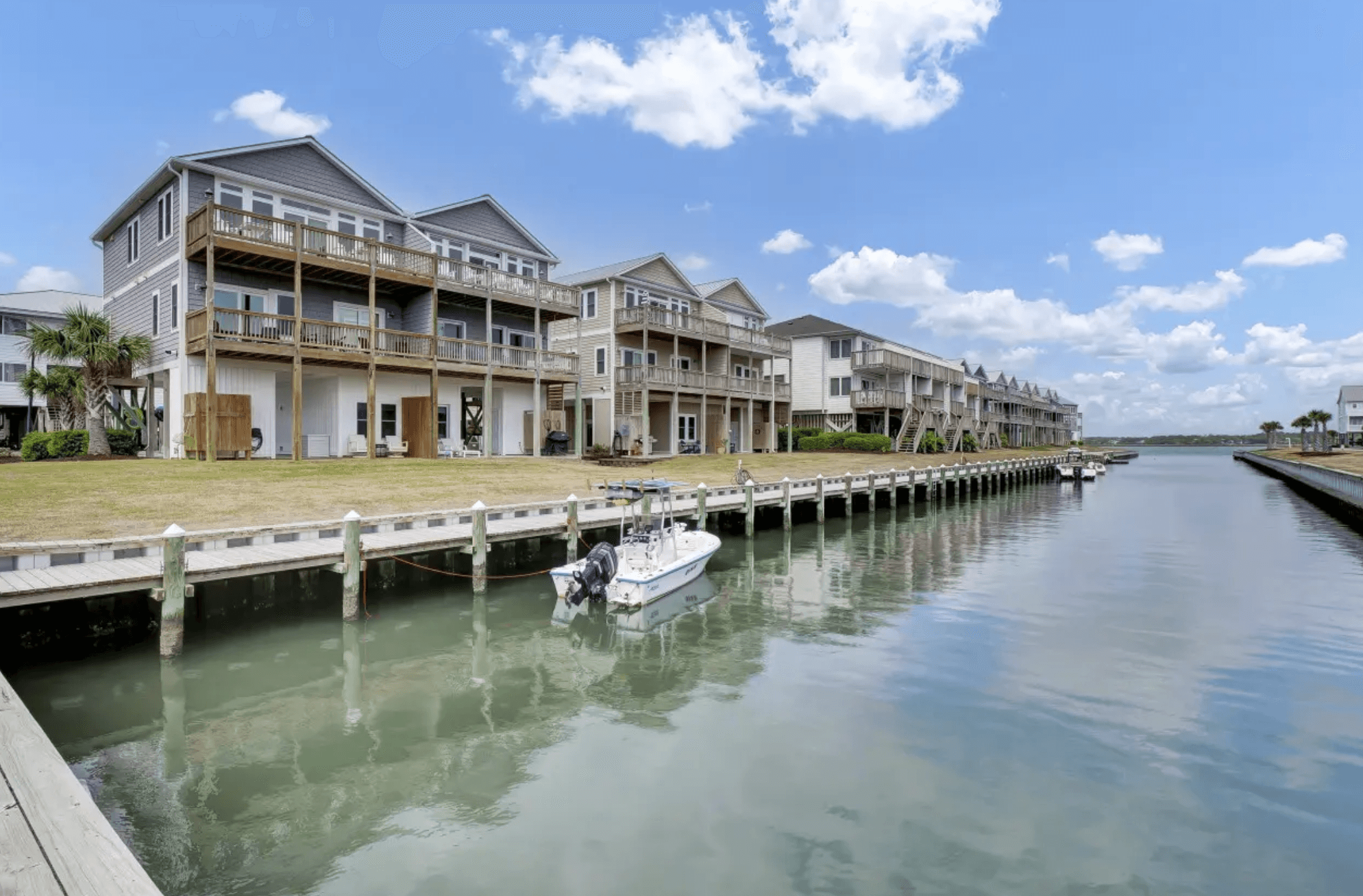 Canal-front townhouses at Queens Grant with a boat docked along the community waterway, Topsail Beach