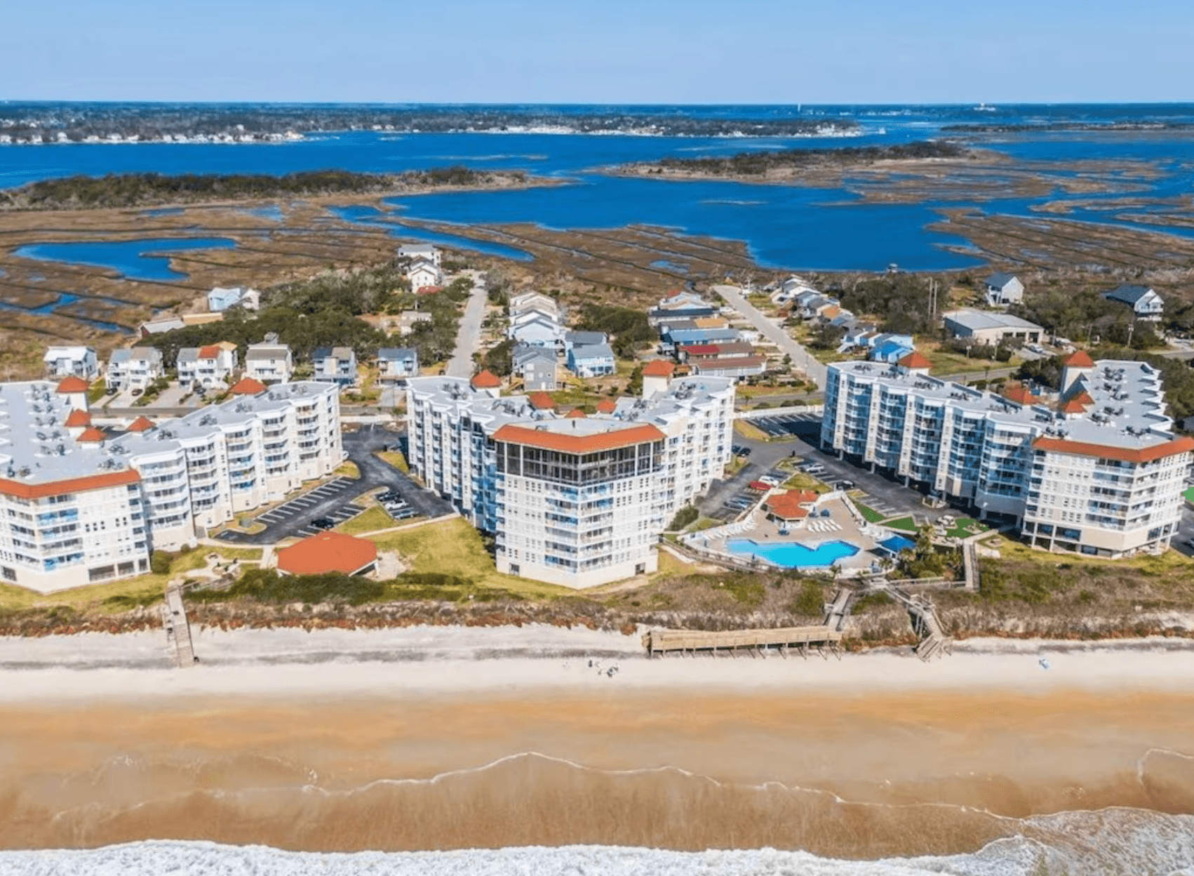 Aerial view of St. Regis Resort in North Topsail Beach with oceanfront buildings, beach, and the sound behind