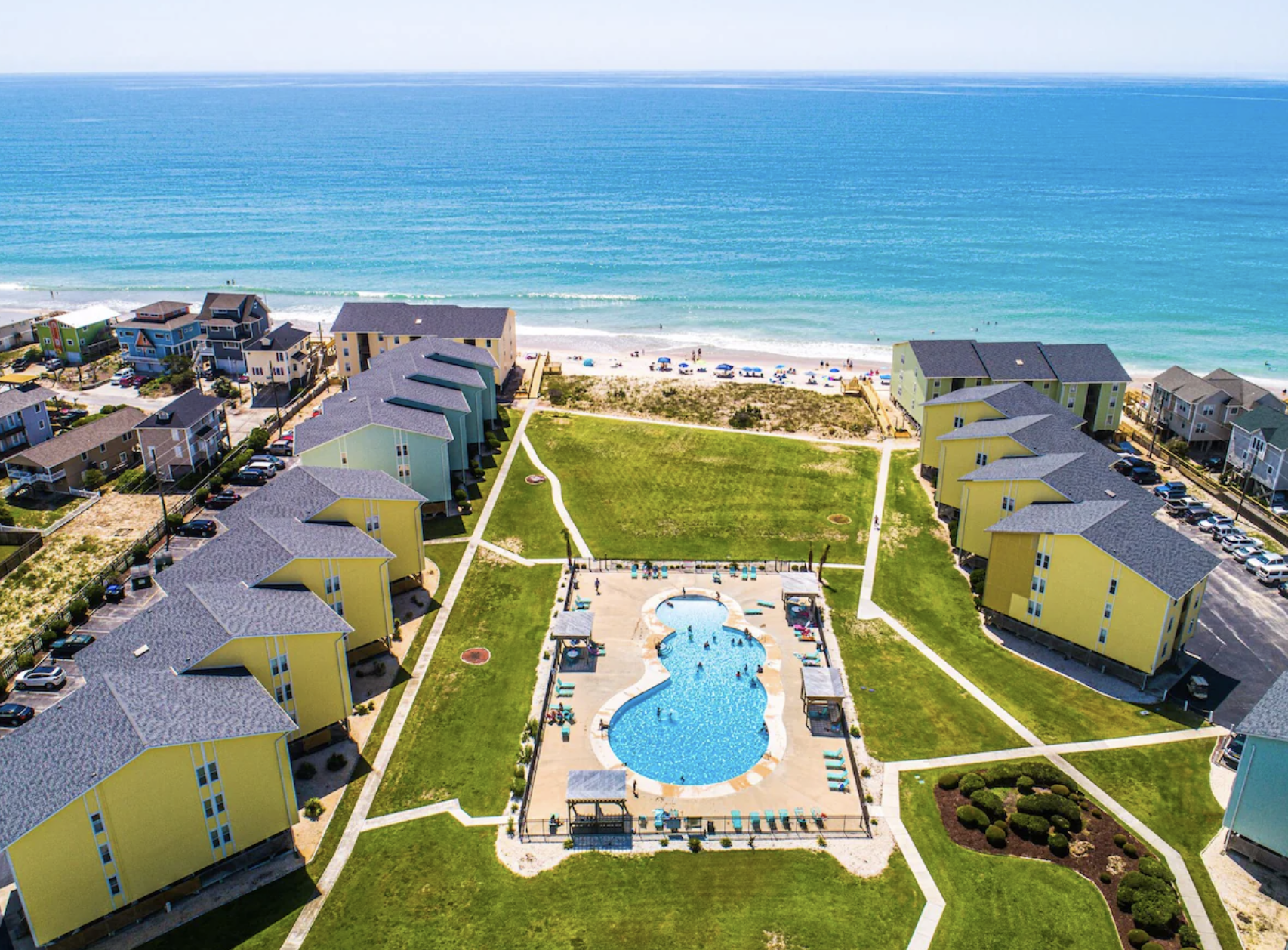 Aerial view of Surf Condos in Surf City with the yellow buildings, community pool, and the Atlantic beyond
