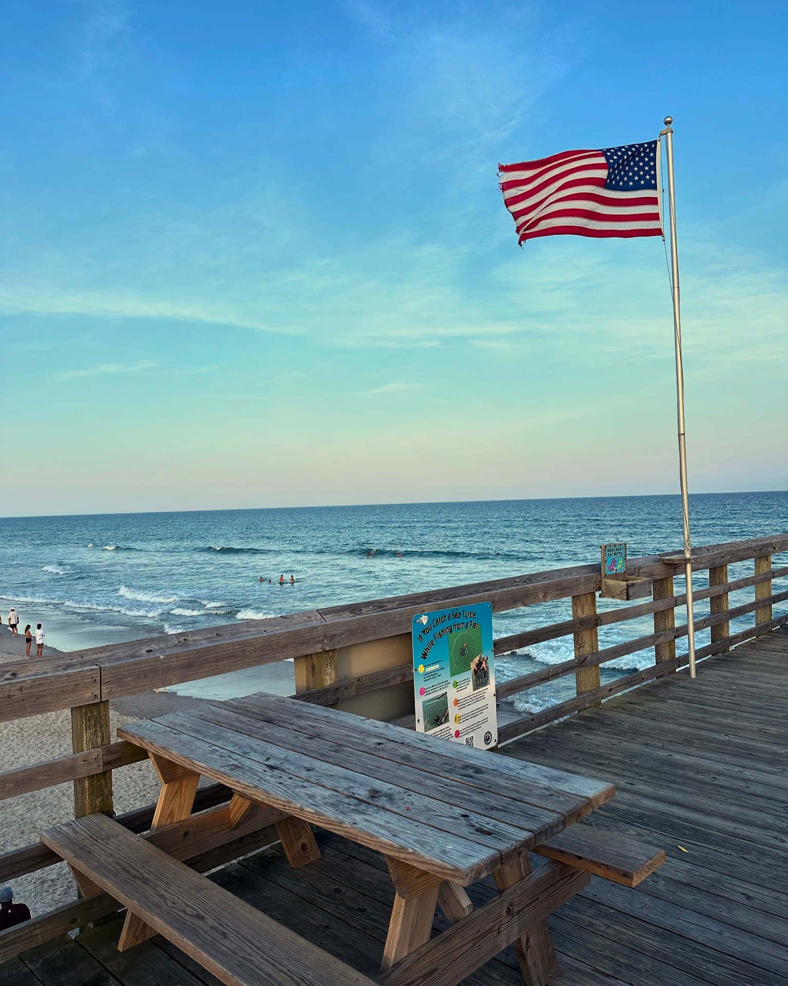 Topsail pier at sunset with an American flag and a picnic table