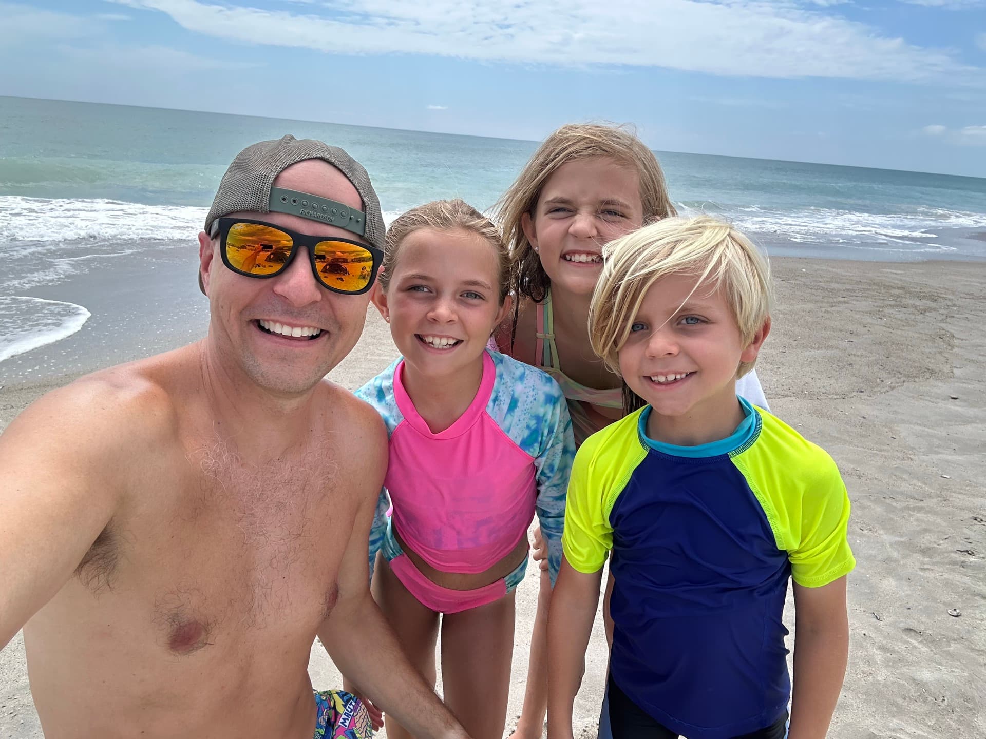 Dad and three kids on Topsail beach with turquoise water behind them