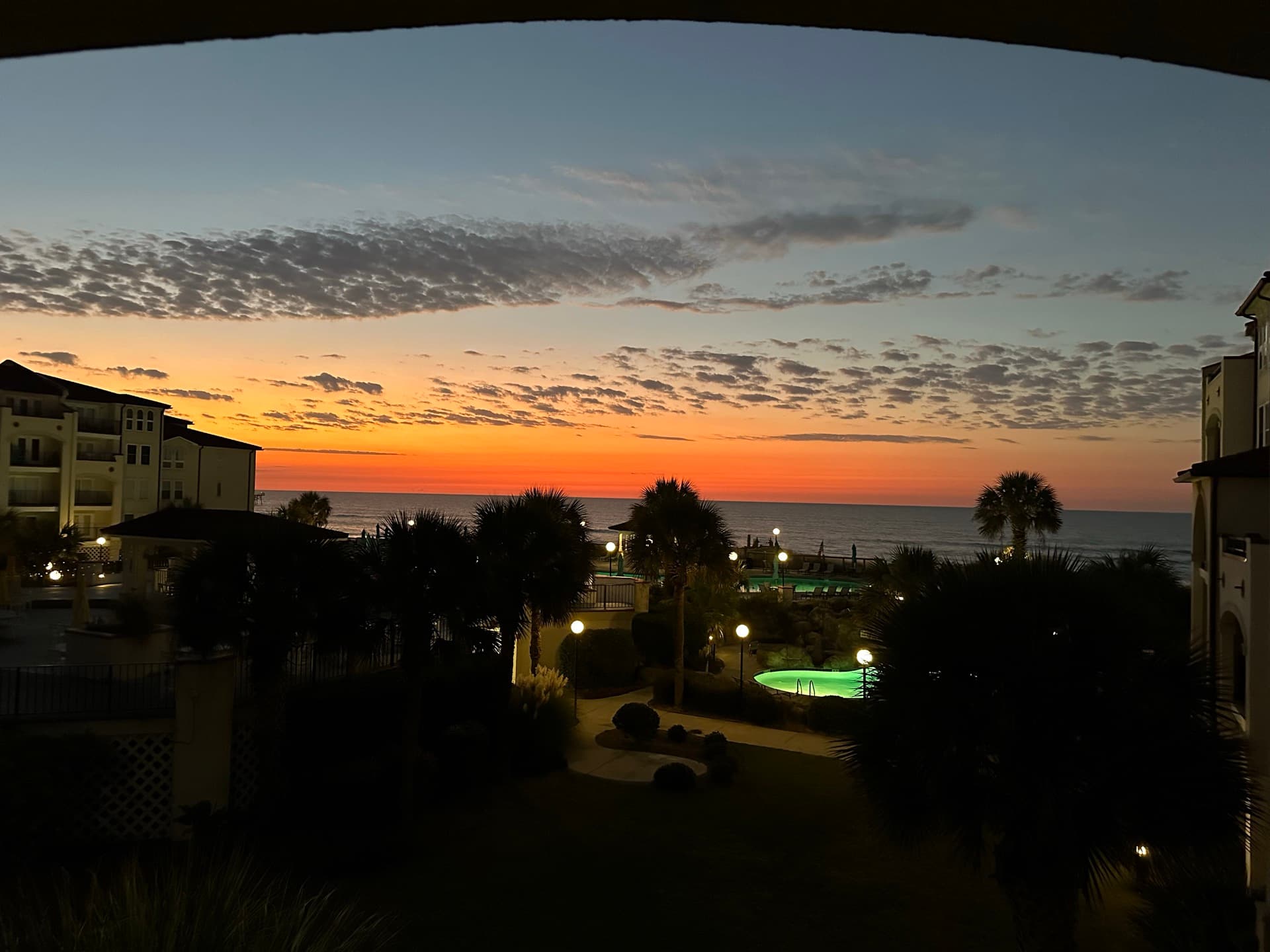 Sunset over the Villa Capriani resort pools from a balcony at Lazy Turtle, North Topsail Beach