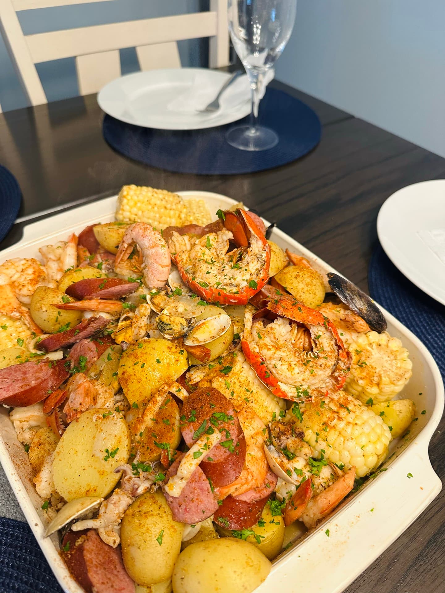 Low country boil platter with shrimp, crab, sausage, potatoes, and corn on a Topsail table